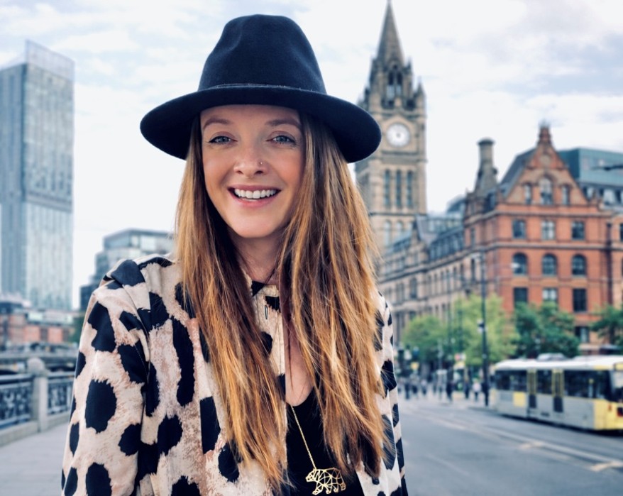 Picture of a smiling woman with a black hat in front of Big Ben and the houses of parliament.