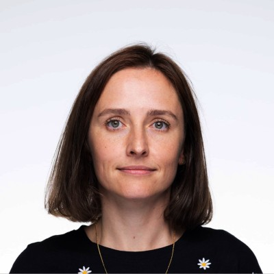 A professional headshot of a woman with shoulder length dark hair. She is looking at the camera.