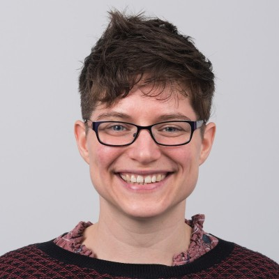 A professional headshot of a woman with short hair and glasses. She is smiling.